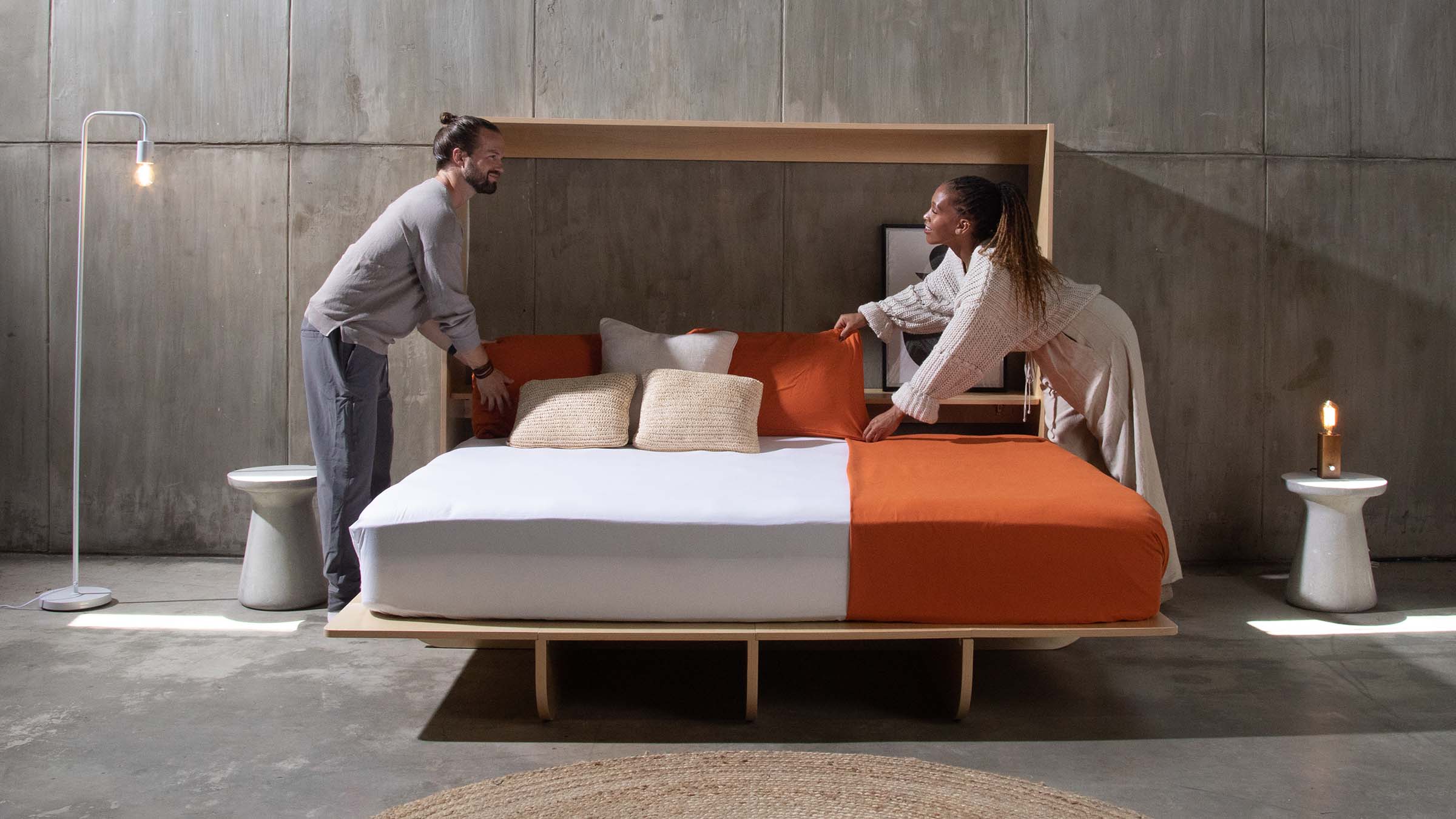 A couple standing beside an open horizontal queen murphy bed looking into each other's eyesurphy bed